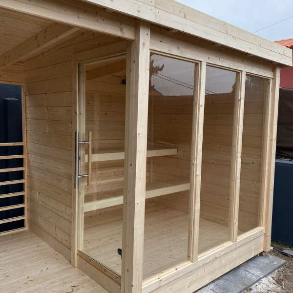 Badstuhytte ANITA terrasse er en plassbesparende badstue med front i herdet glass og glassdør, laget av gran.